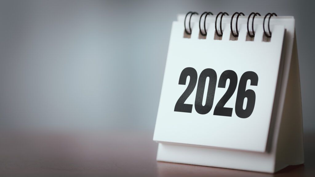 Desk calendar showing 2026 on wooden table with blurred background